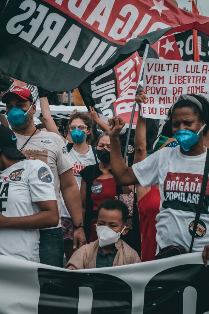 Crowd in Rio de Janeiro protesting, showing support with flags and masks.